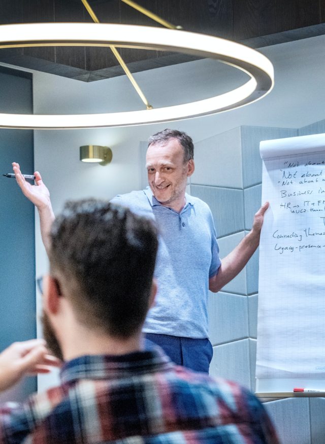 A teacher standing next to a flipchart while giving instruction to a class.