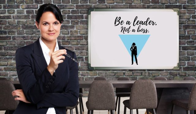 businesswoman-standing-next-to-a-sign-saying-be-a-leader-not-a-boss