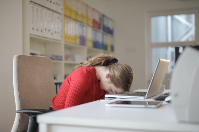 Woman seated with head laid face down on desk