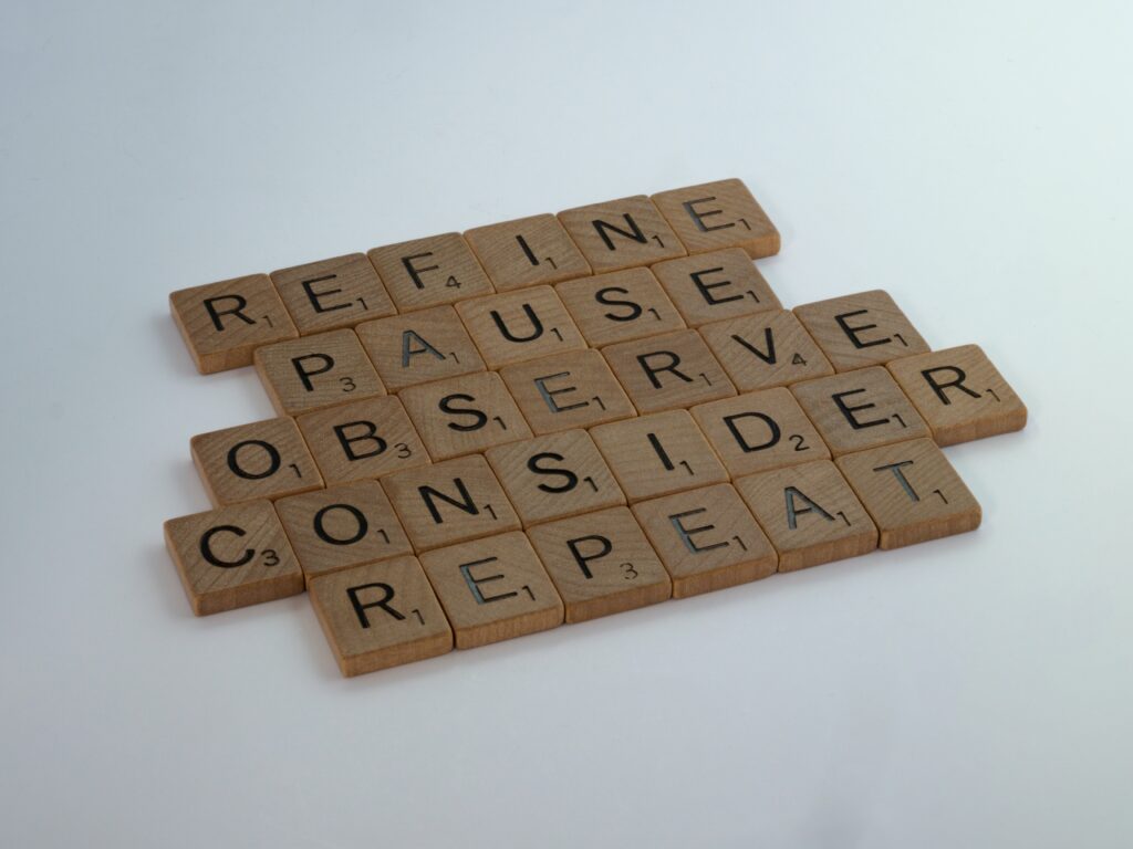 scrabble-tiles-on-blue-surface-spelling-refine-pause-observe-consider-repreat